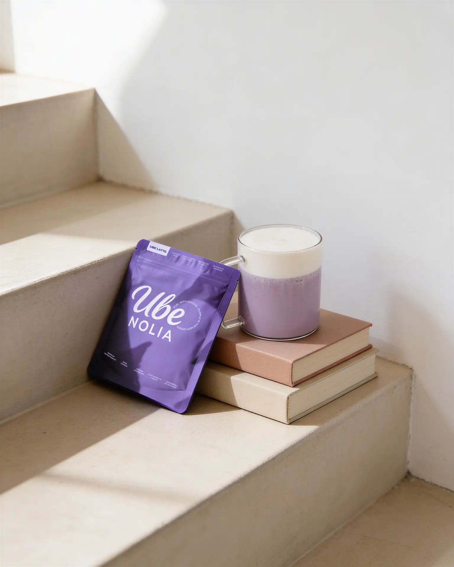 Zak ube poeder van Ube Nolia naast een romige Ube Latte op beige trappen