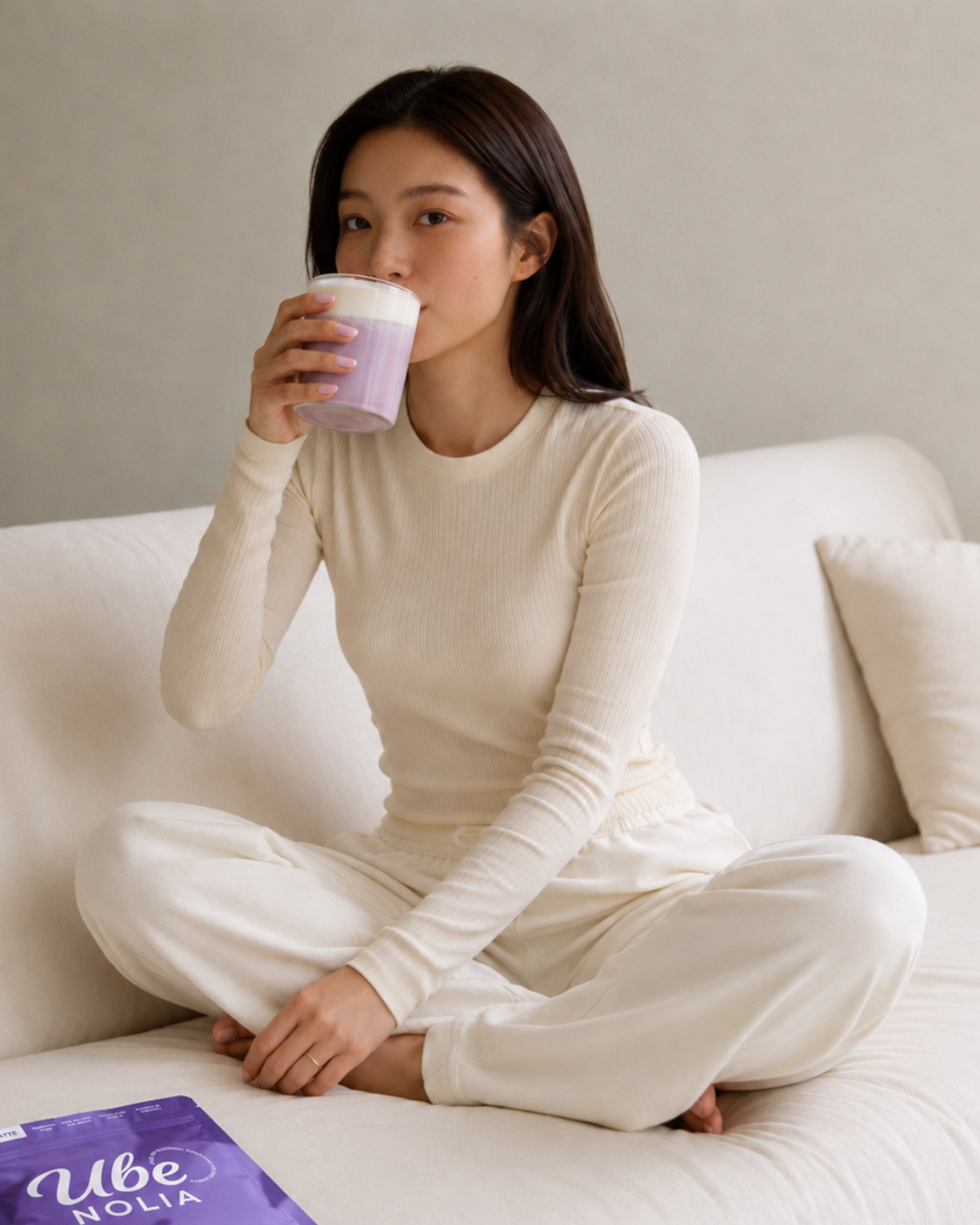 Vrouw drinkt een Ube Latte van Ube Nolia naast de zak ube poeder
